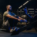 Sport hard weight exercise sporting bodybuilding workout gym pulling rowing machine sitting lift low row motivation healthy African American man sporty male guy athlete sportsman bodybuilder trainer